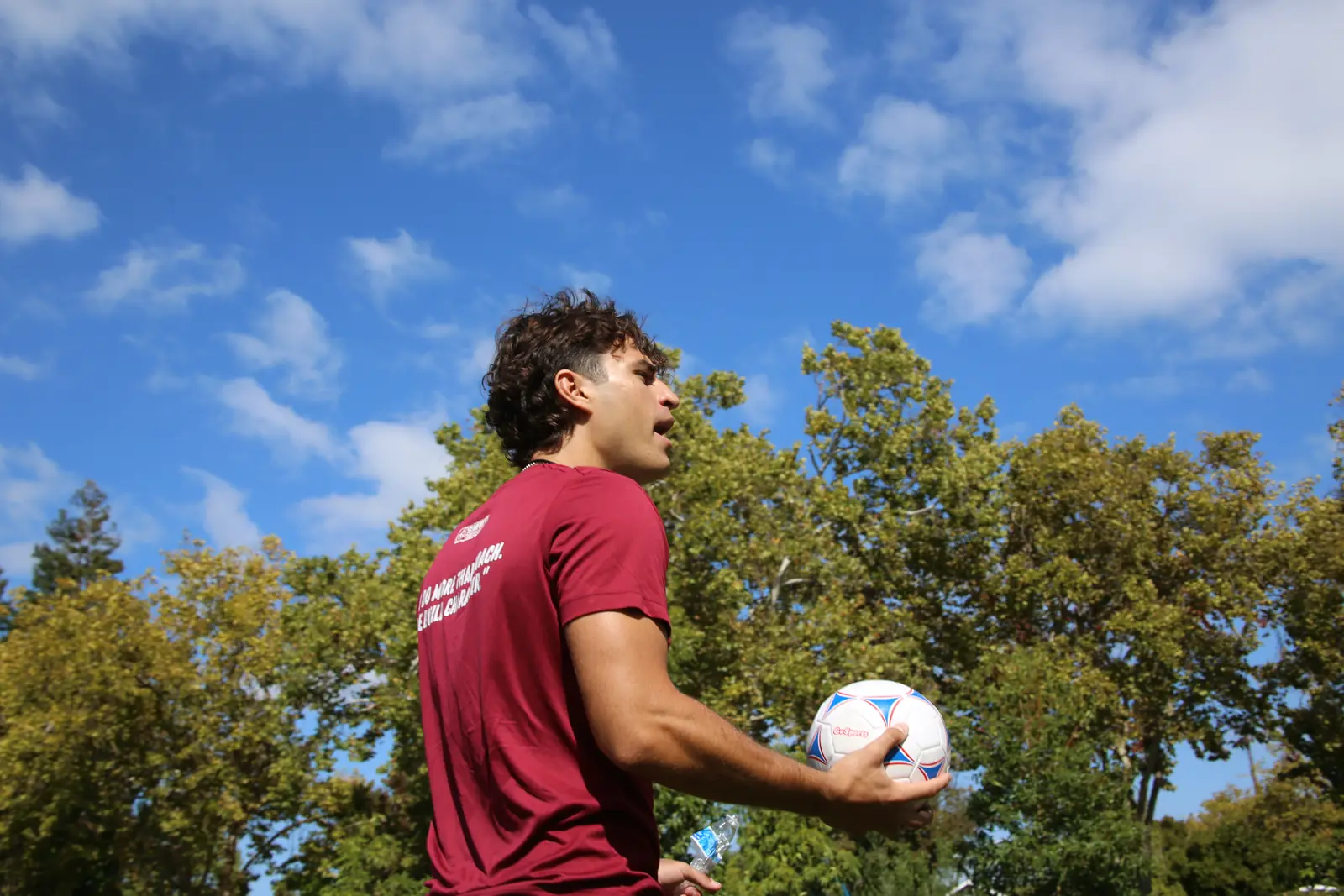 Coach smiling with a soccer ball on the school field