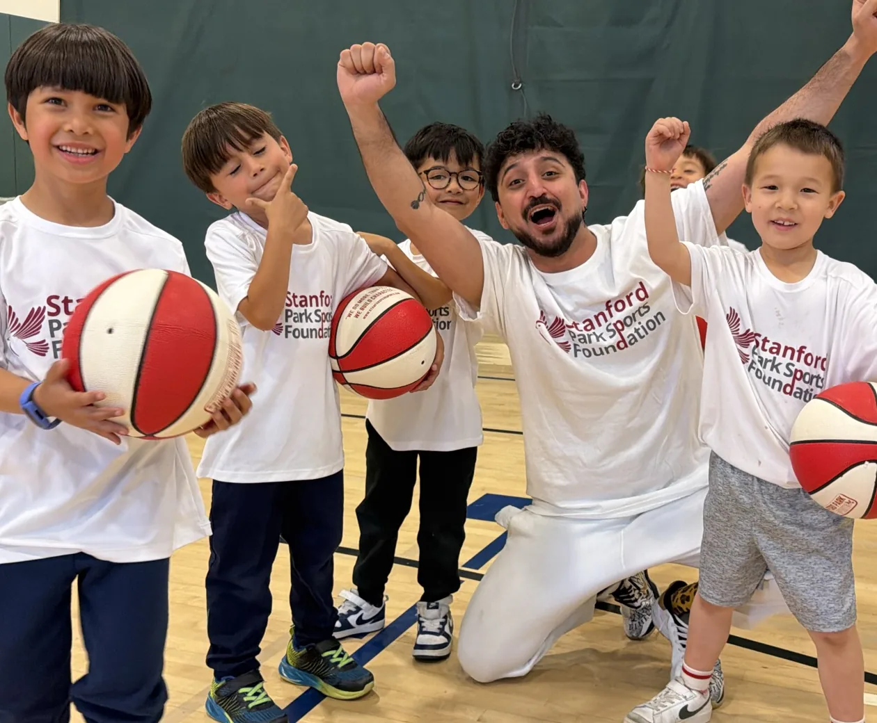 Students cheering with their Stanford Park Sports coach in the school gym