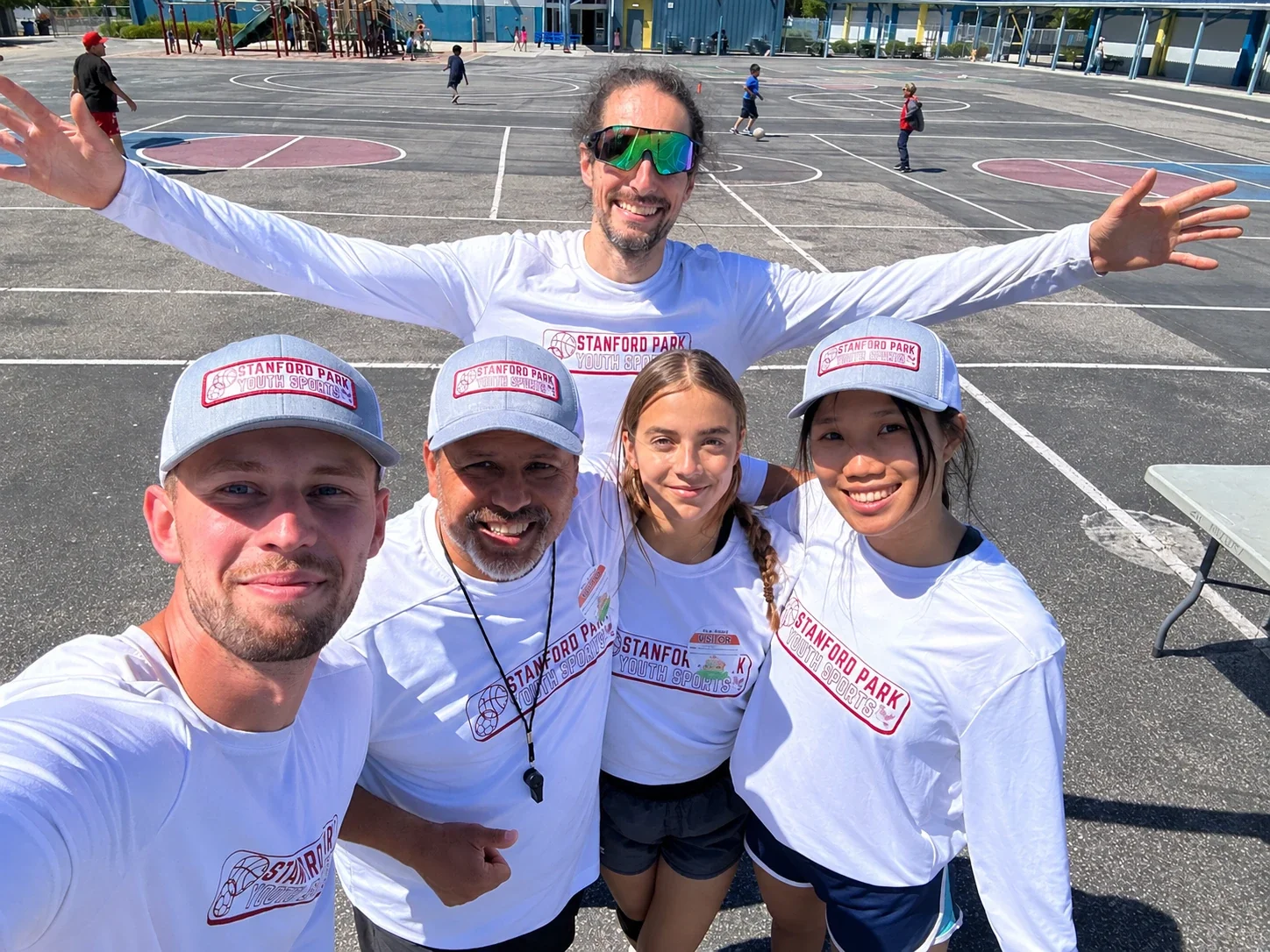 Stanford Park Sports coaching team smiling together on a school blacktop